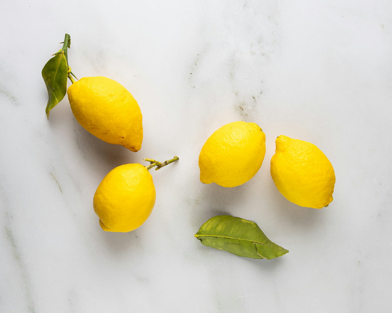 Three lemons and leaves on a marble surface