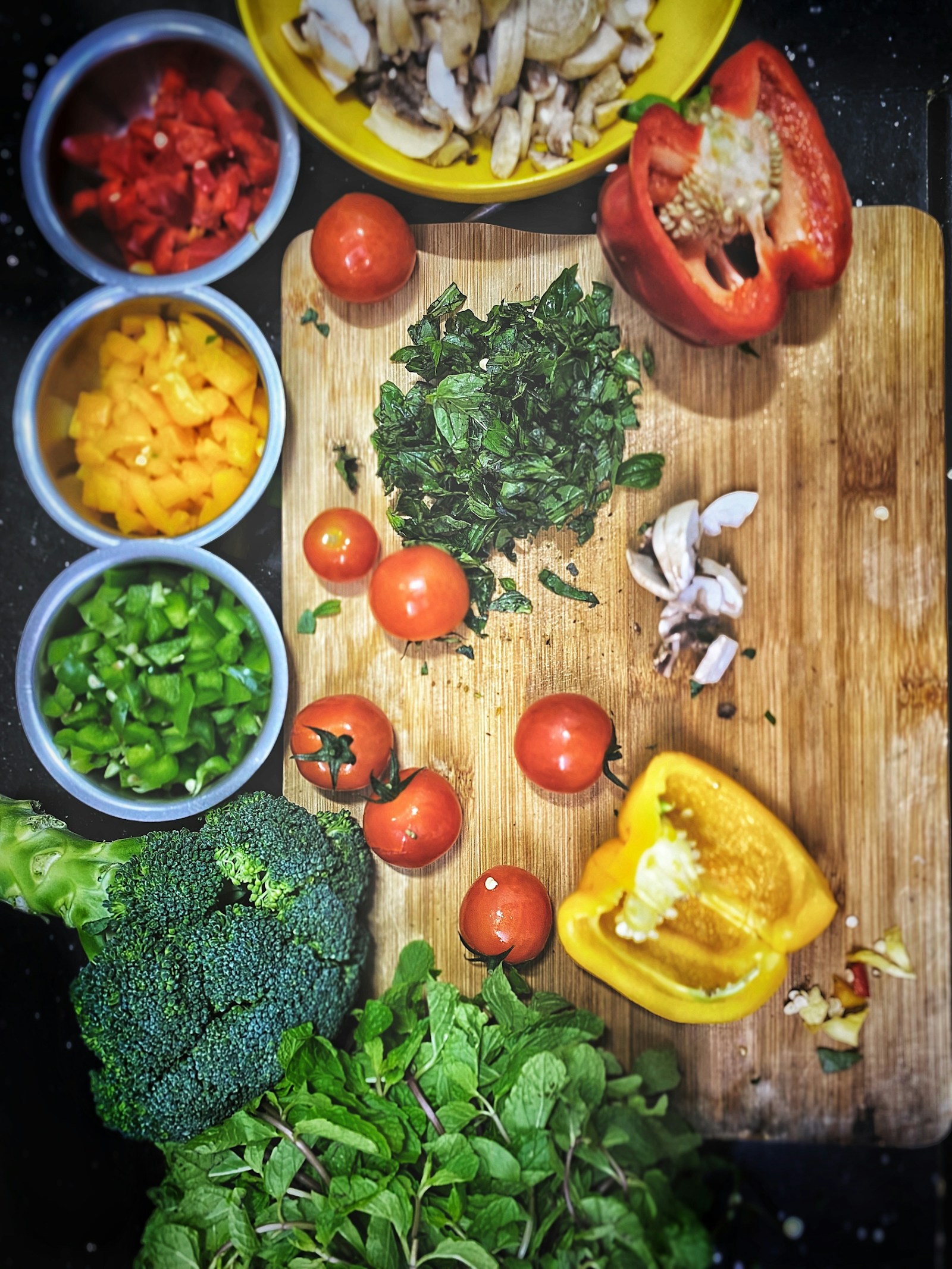 Chopped tomatoes, bell pepper and broccoli on a wooden board